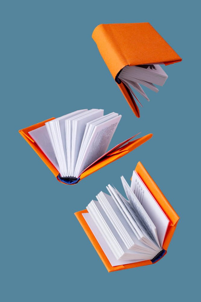 libros-miniatura-cubierta-naranja-vuelan-sobre-fondo-azul